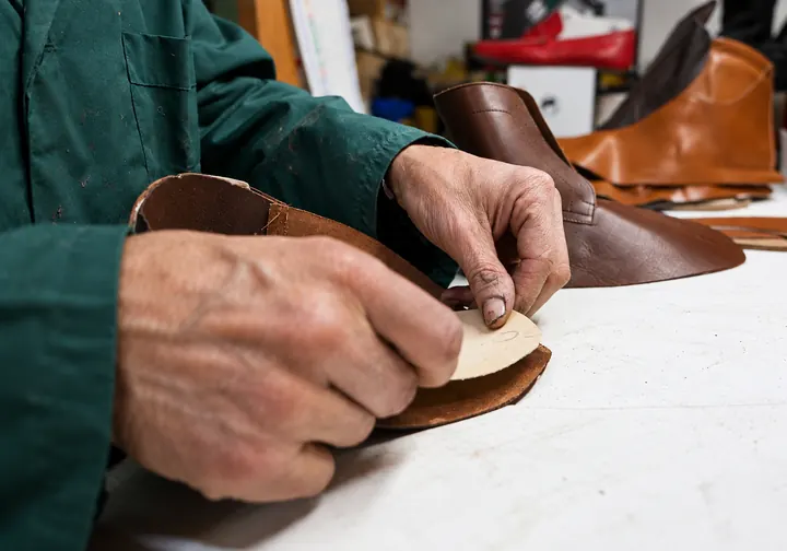 Las manos del artesano colocando el patrón sobre la piel en el taller